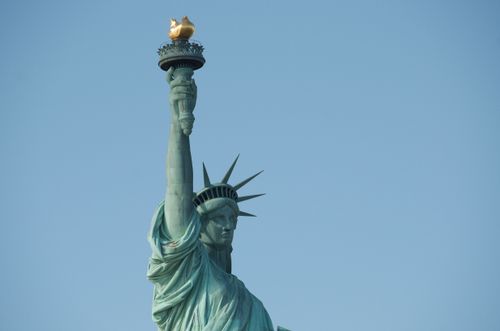 Free Close-up view of the Statue of Liberty's torch and crown against a clear blue sky. Stock Photo