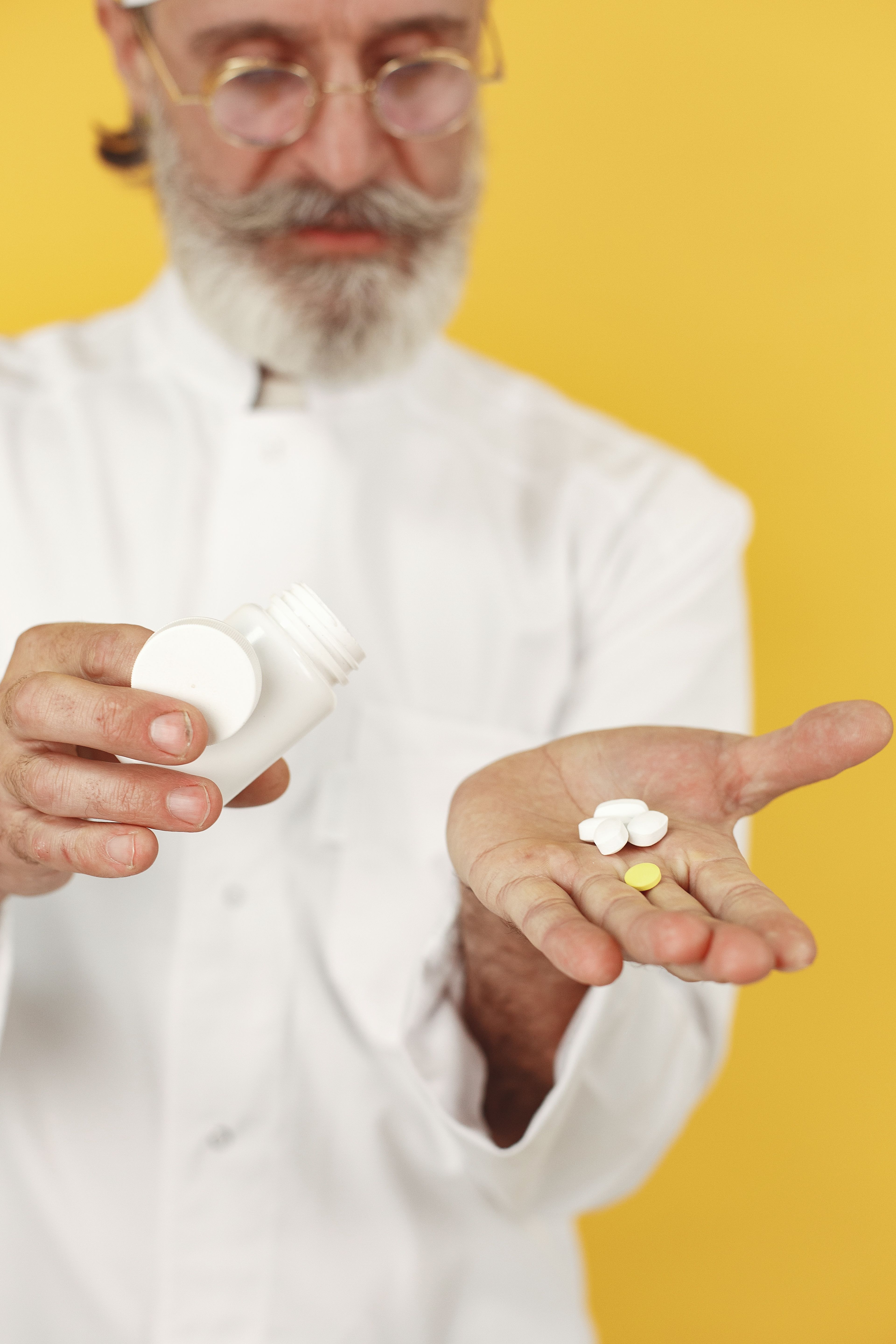 A doctor in a white coat pours tablets from a bottle into a patient's open hand