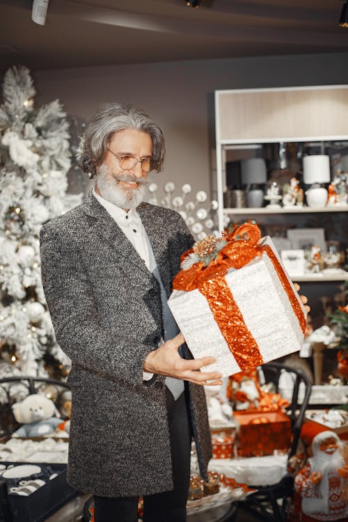 Elderly Man in Gray Coat Holding Christmas Present Box in Store