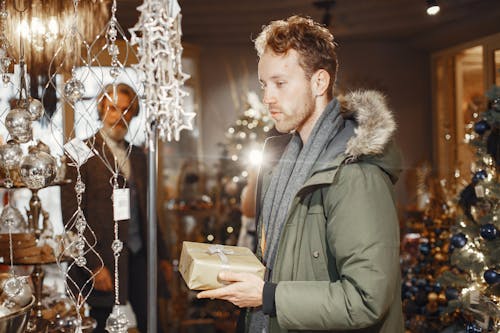 Man in Coat Holding Gift Box in Decoration Store