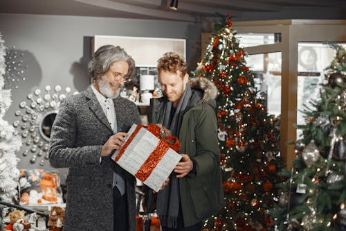 Men Smiling While Looking at the Christmas Present