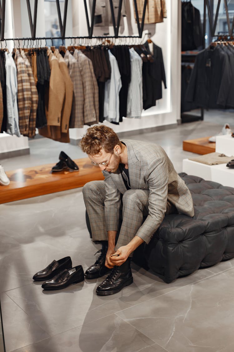 Man In Gray Plaid Suit Tying His Black Boots 