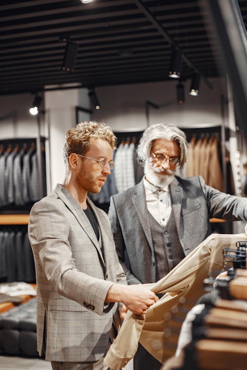 Man in Gray Suit Jacket Choosing a Suit Beside an Elderly Man · Free ...