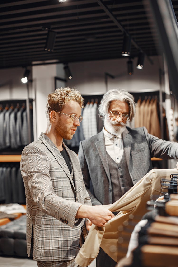 Man In Gray Suit Jacket Choosing A Suit Beside An Elderly Man