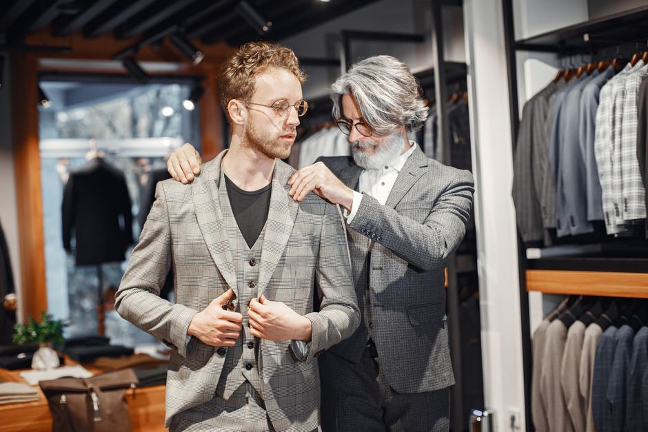 A tailor adjusts a suit for a client in a stylish boutique setting. A tailor adjusts a suit for a client in a stylish boutique setting.