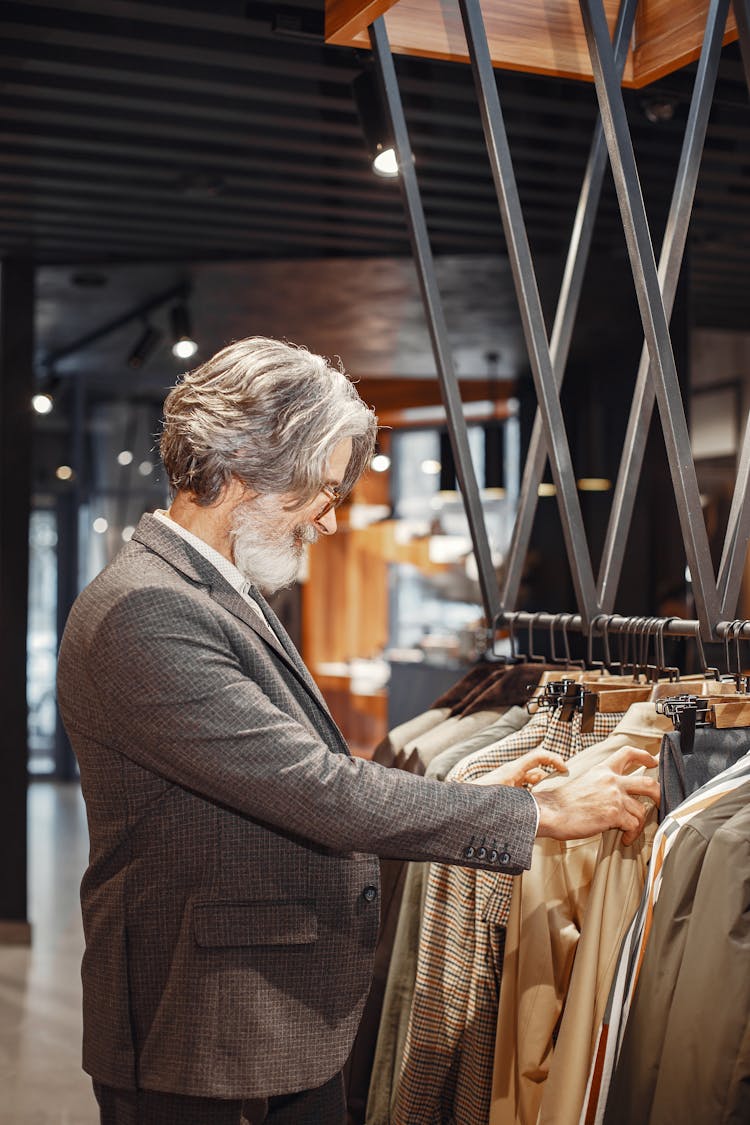 Man In Gray Suit Looking At The Hanging Clothes 