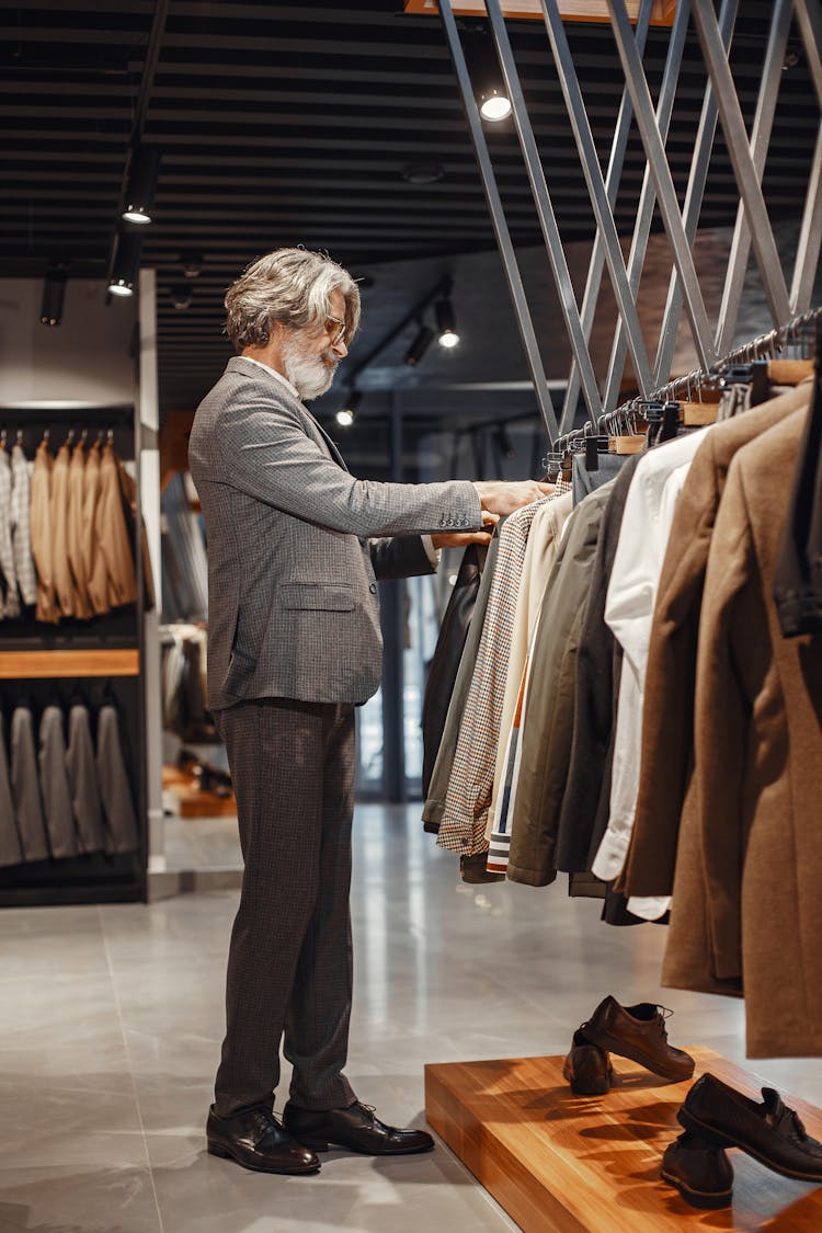 Man In Gray Suit Standing In Front Of Clothes Rack