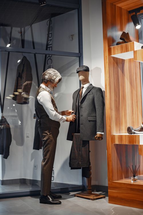 Free A sophisticated tailor adjusts a suit on a mannequin in a stylish boutique setting. Stock Photo