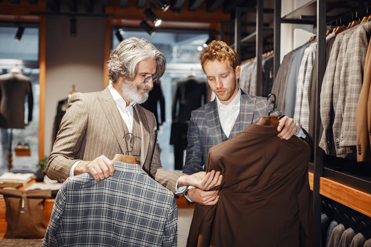 Two Men In Fashion Shop With Suits And Shirts