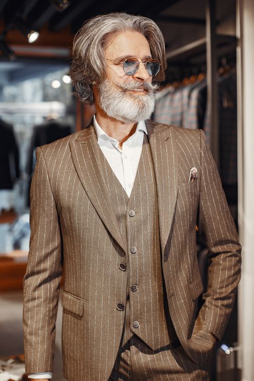 Free Elderly man with beard and mustache poses in elegant pinstriped suit indoors. Stock Photo