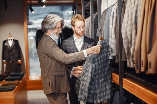 Two men selecting stylish suits in a boutique store, focusing on elegance and style.