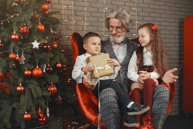 Two Children Sitting On The Lap Of Their Grandfather