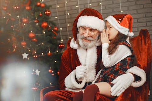 Little Girl Whispering into Santa Clauses Ear 