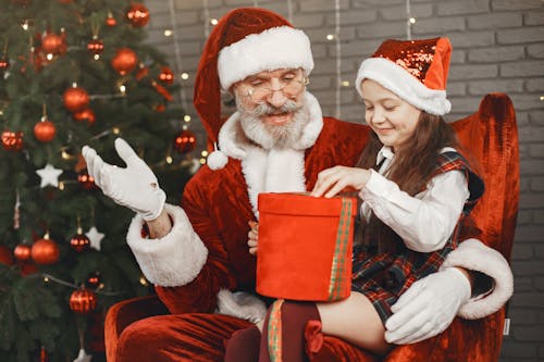 Free Man Dressed As Santa Claus Opening Presents with a Little Girl  Stock Photo