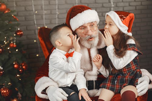 Free Man in Santa Hat Carrying Baby in White Jacket Stock Photo