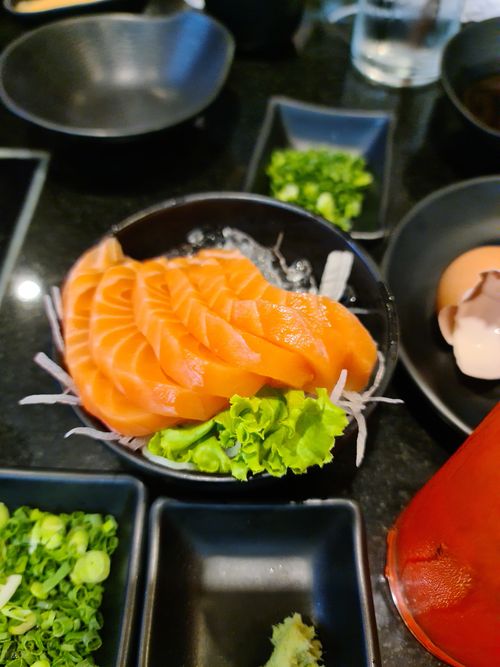 Free Close-up of fresh salmon sashimi served with garnish in a Thai restaurant, showcasing food presentation. Stock Photo