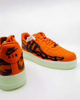 Close-up of orange Nike sneakers featuring black flame details and white soles with ample copy space.