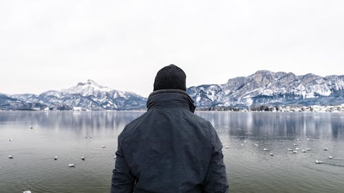 Back View of a Person in Winter Clothes Standing near the Lake