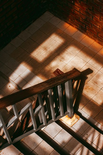 From above of stairway with metal banisters and tiled steps in building with brick walls on sunny day