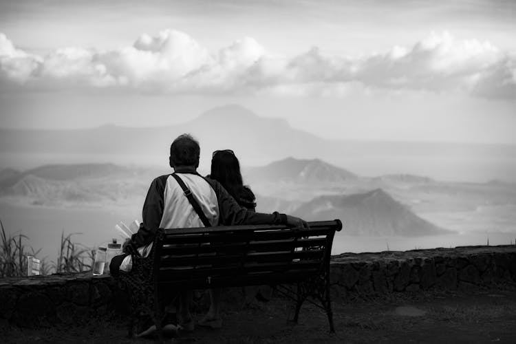 Anonymous Travelling Couple Resting On Bench And Enjoying Mountain View