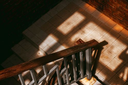 Free From above of wooden and metal banister of stairway with tiled floor in brick building on sunny day Stock Photo