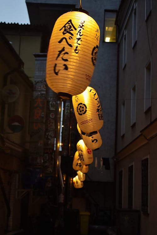 Vertical Shot of Yellow Lanterns with Japanese Script on a Dark Street