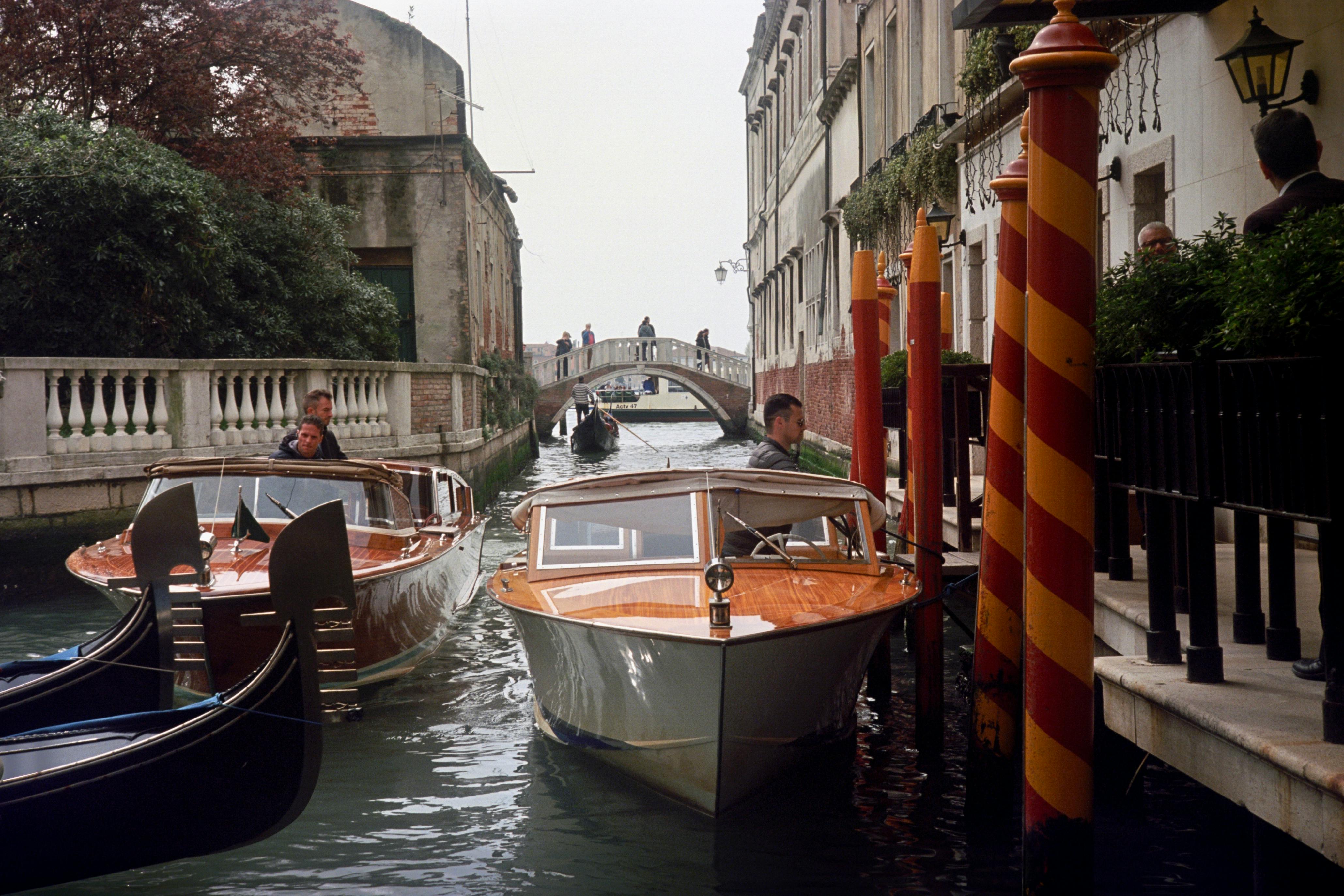 A picturesque scene of boats navigating a canal in Venice with a classic bridge in the background.
