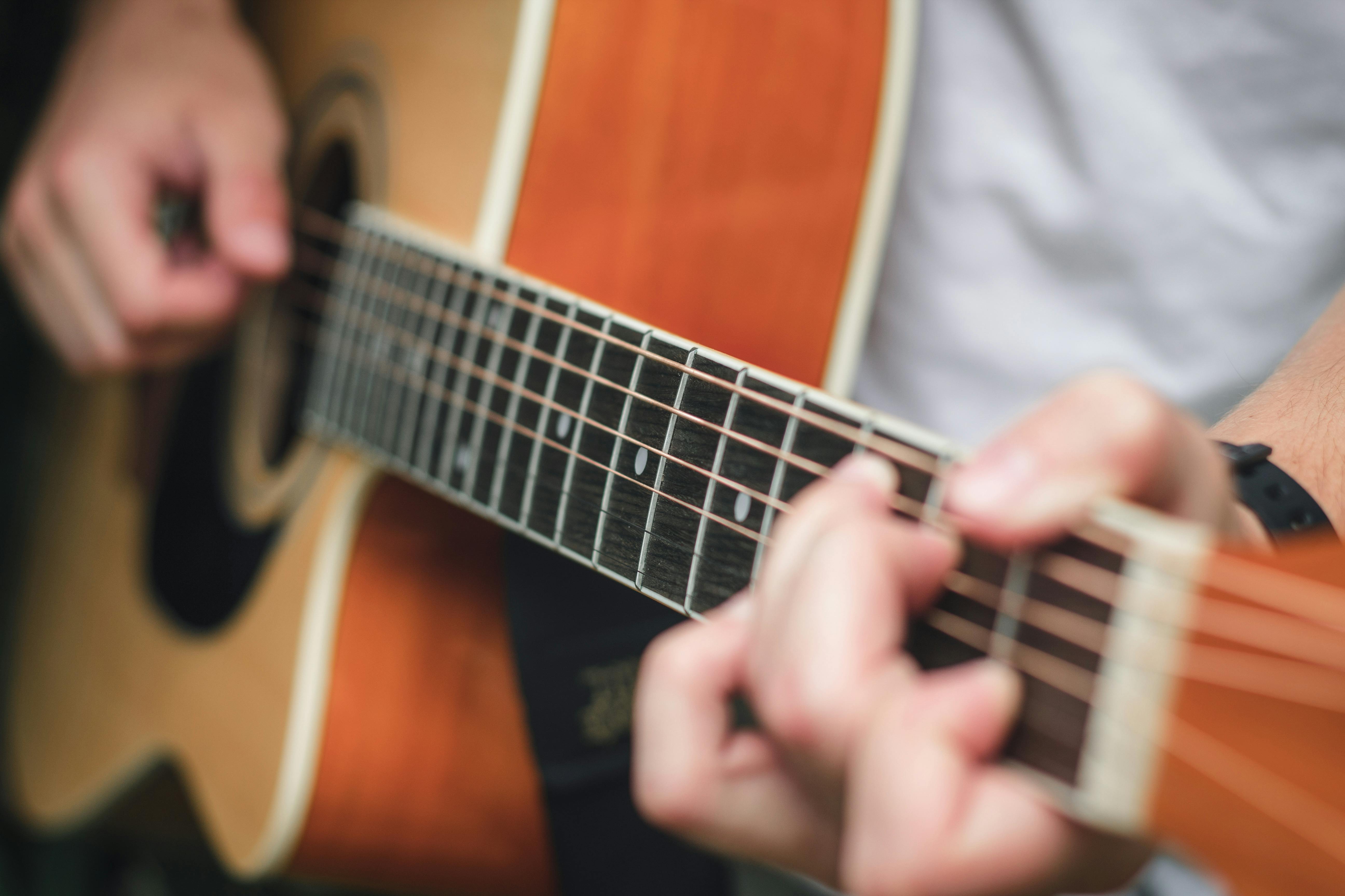 guitarist pinching chord while playing acoustic guitar