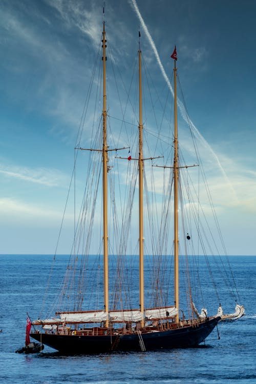 Black Sail Boat on Sea Under the Blue Sky