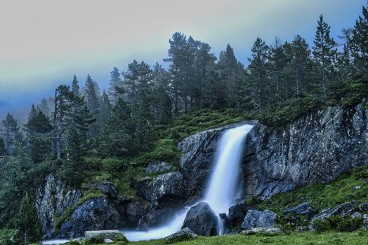 Explore the serene beauty of a cascading waterfall in Lérida, Spain, surrounded by lush greenery.