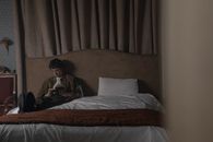 A man enjoying a quiet reading moment in a cozy, dimly lit bedroom.