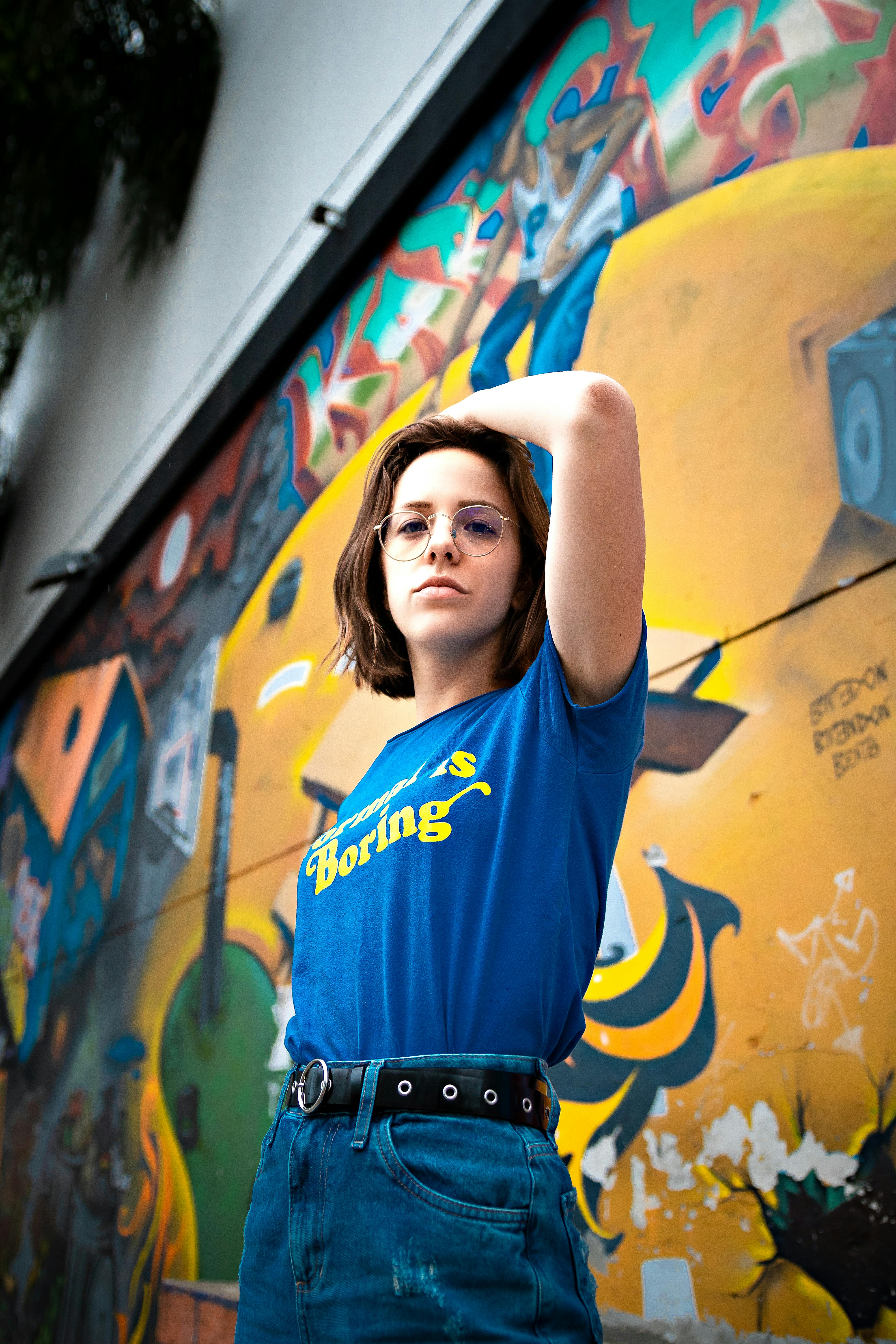 serious young lady touching hair near graffiti wall