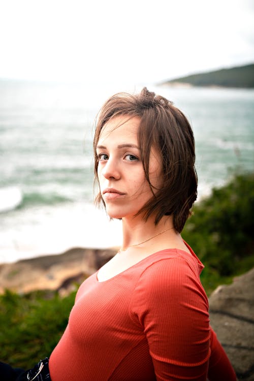 Peaceful young woman recreating on rocky seacoast on cloudy day