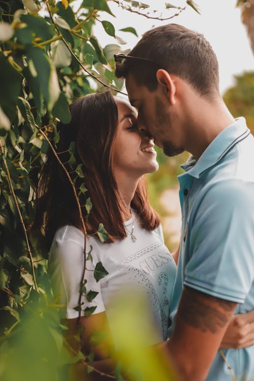 Man and Woman Kissing Beside a Plant