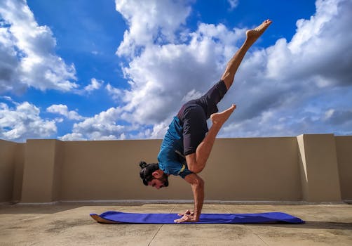 Man practicing a dynamic yoga pose on a rooftop under a vibrant blue sky with clouds.