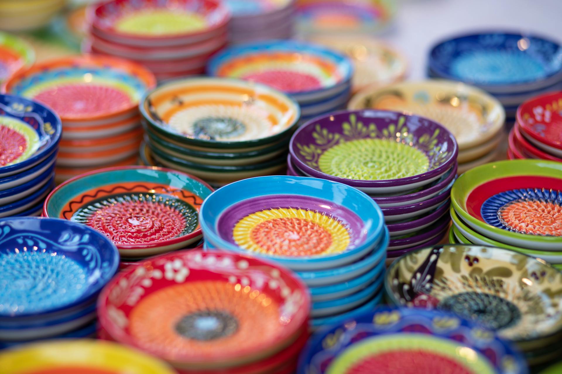 Colorful ceramic plates stacked with intricate patterns, showcasing craftsmanship in an artisan market setting.