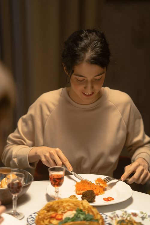Free A woman sits at a dining table, enjoying a festive meal indoors. Stock Photo