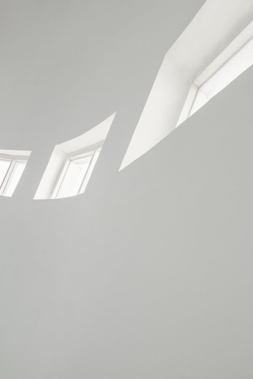 Free A modern minimalist interior featuring white geometric windows providing airy lighting. Stock Photo