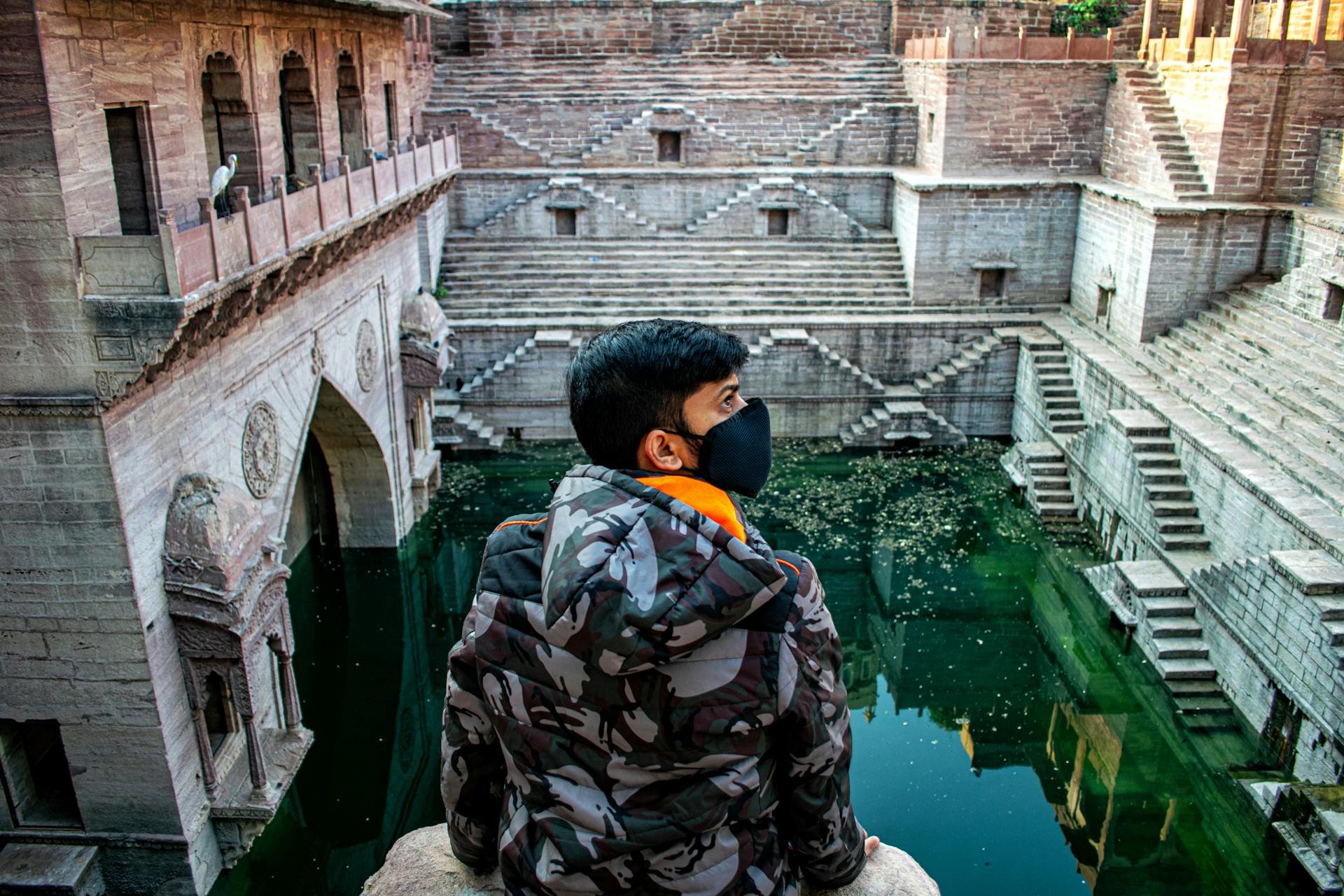 A Man in a Face Mask Sitting at the Toorji Ka Jhalra Bavdi