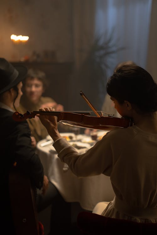 Woman Playing Violin At A Dinner Table During Hanukkah Celebration