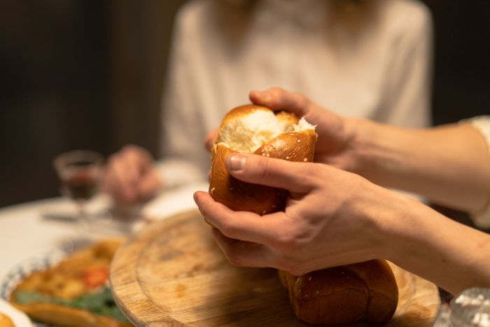 Hands tearing fresh challah