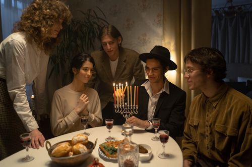 Free A joyful Hanukkah gathering with family lighting the menorah and enjoying traditional foods. Stock Photo