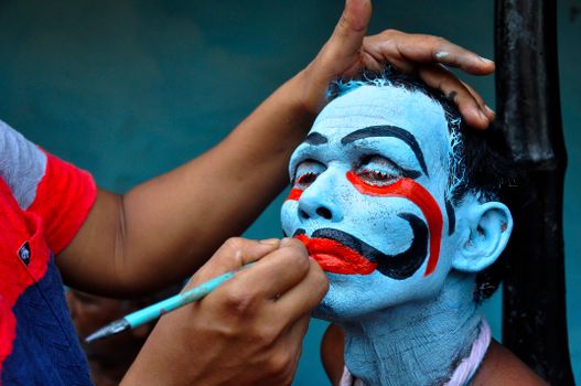 A man being painted with traditional face paint for an Indian festival.
