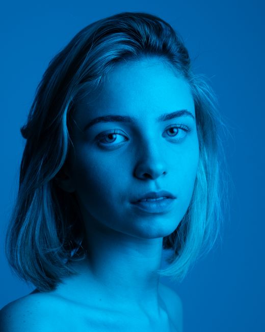 Artistic blue-toned headshot of a woman with a calm expression.
