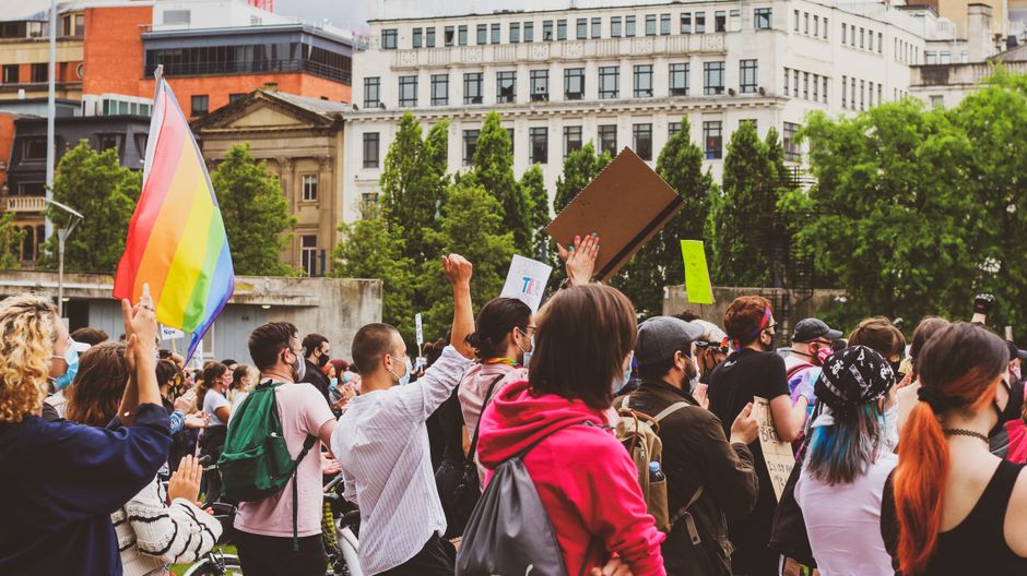 Activistas LGBT con pancartas y bandera arcoíris protestando en una calle de la ciudad.