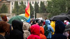 People in Orange and Black Jackets Standing on Road
