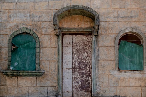 Facade of aged abandoned stone house with shabby wooden door and windows in old town