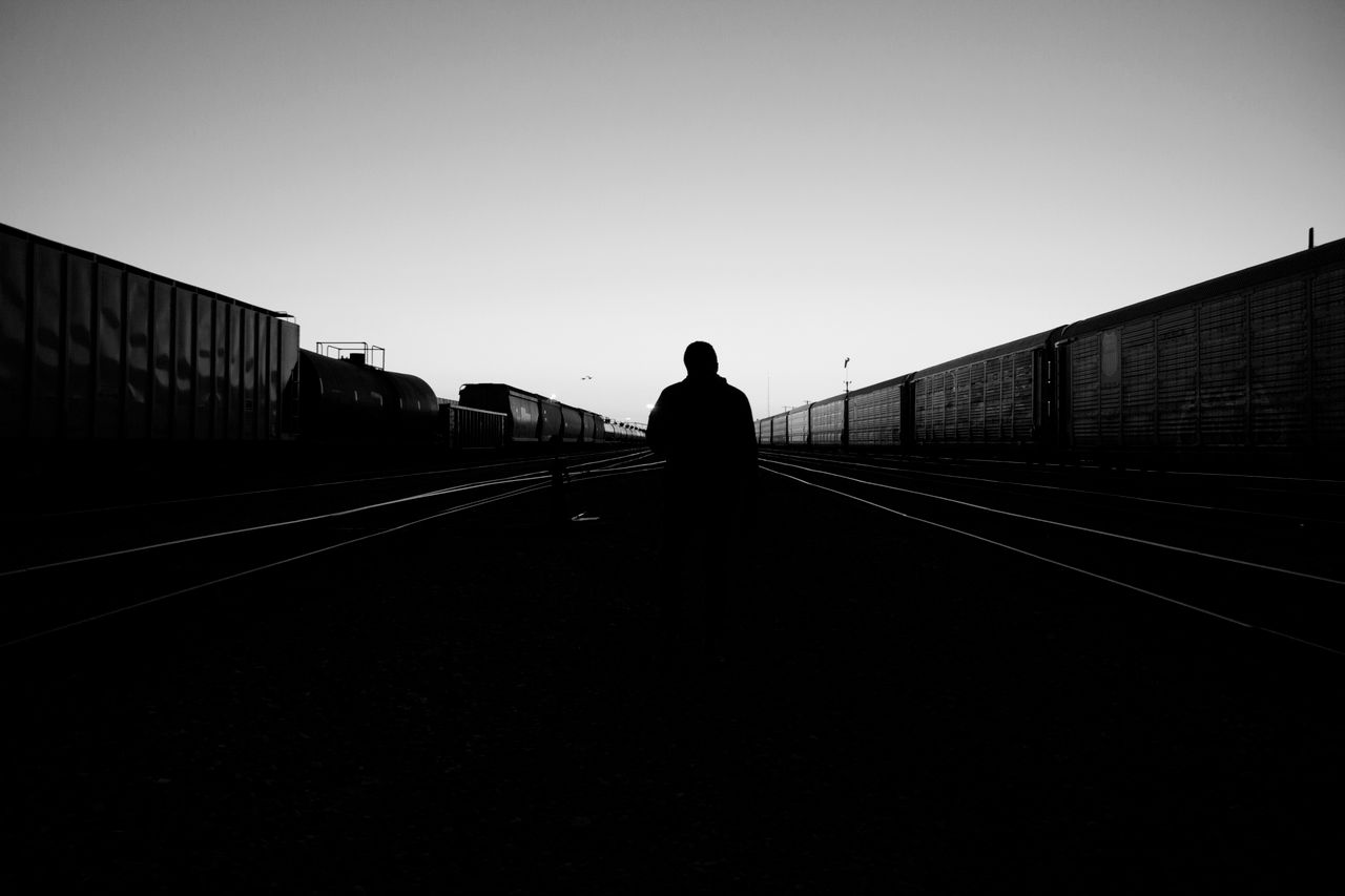 moody black and white photo of a lone silhouette walking along empty r