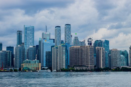 Scenic view of Toronto's skyline featuring skyscrapers and a waterfront under cloudy skies.