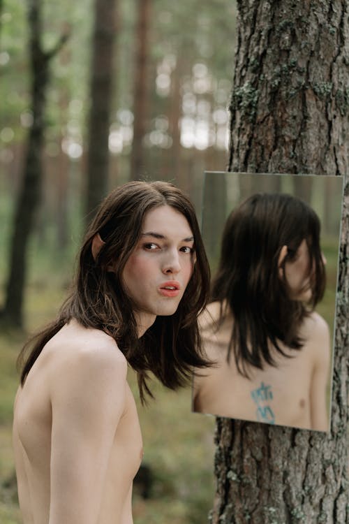 Topless Person Standing near the Hanging Mirror 